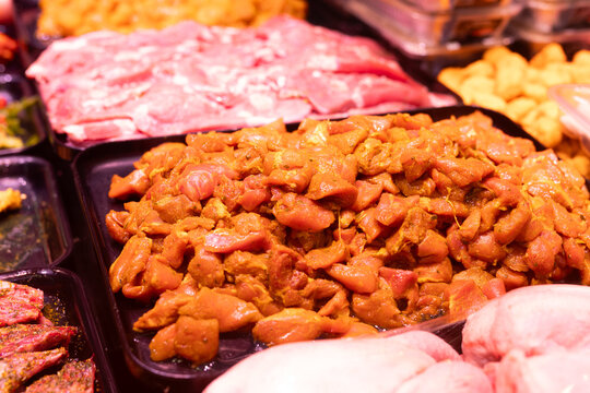 Meat department of store sells chicken meat marinated with addition of curry seasoning.