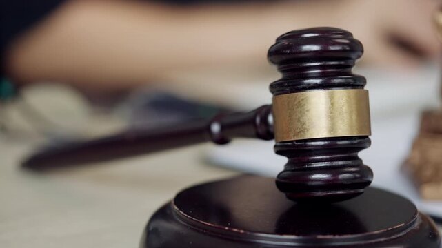 Wooden judge gavel displayed in the foreground with legal paperwork and a professional office environment in the background. Ideal for law firms, legal services, court decisions, business law, complia