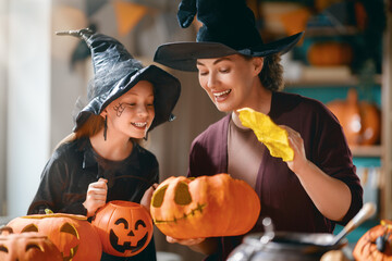 Obraz premium Happy Family Halloween Pumpkin Carving at Home, Mother and Daughter