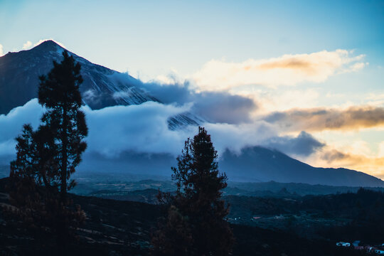 A volcano Teide and mountains among clouds at sunset.
