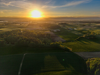 Atmospheric aerial view over the Polish countryside at sunset, with glowing horizon, darkened fields, and a calm rural scene near Barkoczyn. © Lukasz