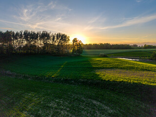 Wide aerial view of the Polish countryside near Barkoczyn, with green rolling fields, rural buildings, and soft evening light. © Lukasz