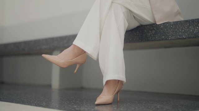 Elegant close-up of women's professional attire featuring tailored trousers and classic high heels in a modern office environment. Perfect for corporate fashion, executive lifestyle, workplace style, 