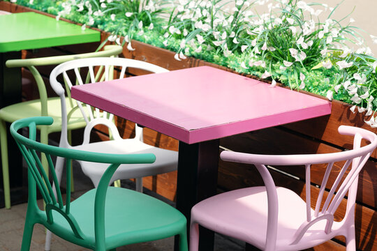 Empty modern outdoor street cafe terrace furnished with colorful plastic chairs and dining tables.