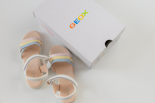 Unboxing new Geox girls sandals with multicolored pastel straps in branded white box over white background