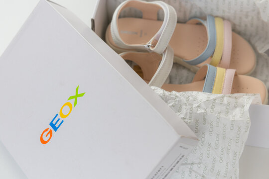 Unboxing new Geox girls sandals with multicolored pastel straps in branded white box over white background