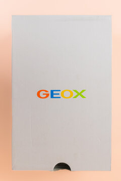  Top view of white Geox shoebox with colorful brand logo on light pink background