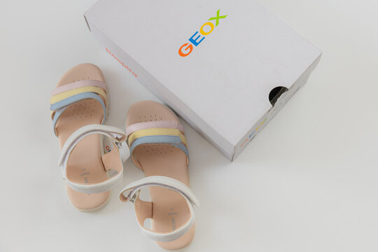 Unboxing new Geox girls sandals with multicolored pastel straps in branded white box over white background