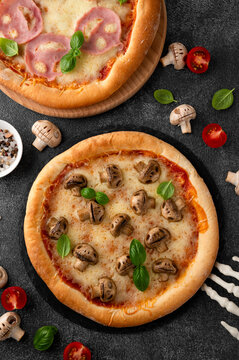 Halloween mushroom pizza with basil, cheese and spooky skeleton decoration on a dark background, creative food concept for seasonal menus. Funny food idea. Top view.