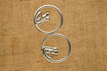 Spiral metal curtain rod in satin nickel color on jute fabric, close-up. © Oleksandr