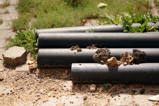 Polyethylene plastic utility pipes lying on ground ready for underground water pipeline construction project.