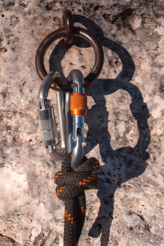 Climbing gear, carabiners, rope and anchor in  a rocky mountain closeup.