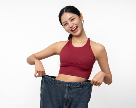 Young asian woman thin slender abdomen waist wearing old big jean after her success weight loss diet session. Care about eating and workout exercise for slim fit and firm good shape