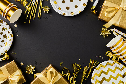 Golden party decor and gift box frame on black background