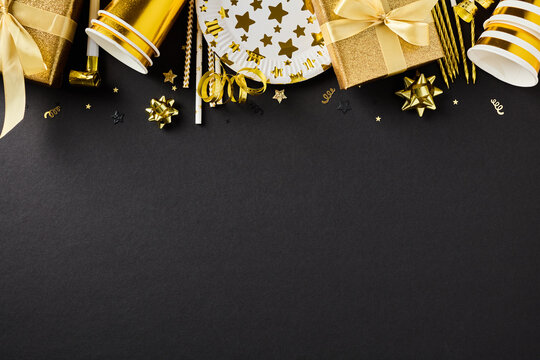Golden birthday party decor top border on black background flatlay