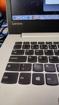 ITABIRA, BRAZIL - JULY 26, 2026: Vertical close-up of a Lenovo laptop showing Zorin OS Linux running on the screen above a keyboard with a Windows logo key, highlighting open-source operating system m