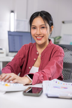 Asian woman office worker smile desk computer keyboard report smartphone young professional working at modern office with confident expression Vertical