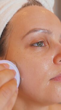 Woman using a microcurrent device on her cheek during a facial treatment, performing a daily beauty routine focused on skin rejuvenation, anti aging, and wellness in a close up spa setting