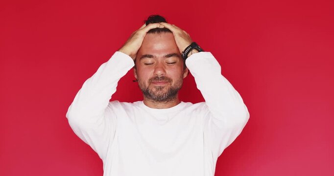 Stressed desperate middle aged Caucasian man screaming holding head in hands with open mouth from shock mistake failure panic problem feeling overwhelmed on red studio background video concept clip