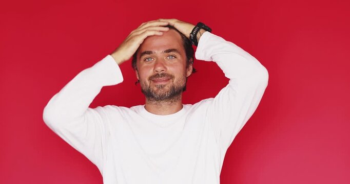 Handsome middle aged Caucasian man holding head fixing hair then getting brilliant new idea pointing finger up with joyful smile on red studio background, eureka solved problem 