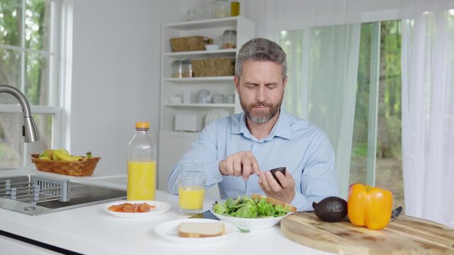 Man focused on healthy breakfast in the kitchen in the morning. Morning kitchen scene with a man and clean diet. Man preparing a light morning meal in the kitchen. Kitchen morning concept with a man.