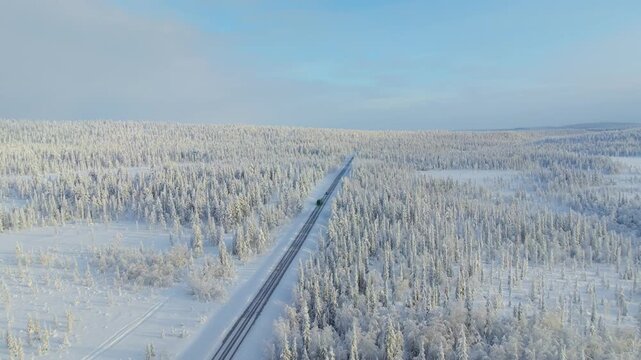 Aerial drone view of a road through a snowy winter pine forest. Flying over a snow-covered road in winter forest, Christmas travel concept.