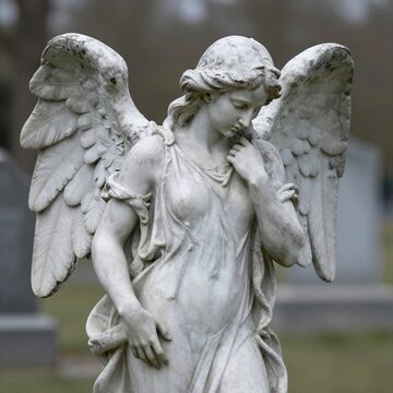 Close-up of an ancient weathered marble angel statue in a cemetery