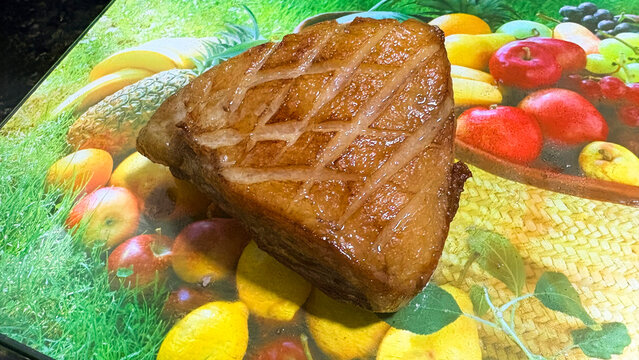 Cooked sirloin steak with scored fat on fruit background