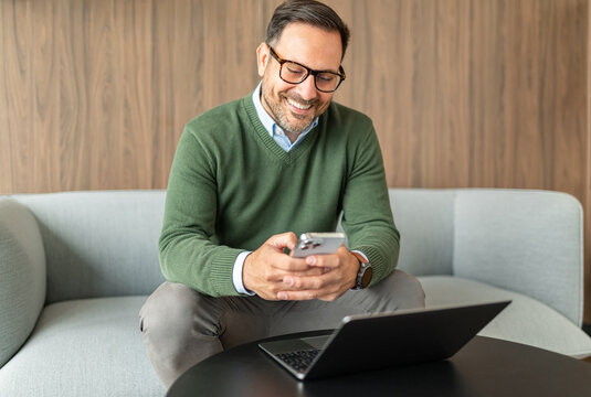 Entrepreneur smiling while looking at a smartphone, working remotely and managing business communications with accessible technology in a contemporary office environment