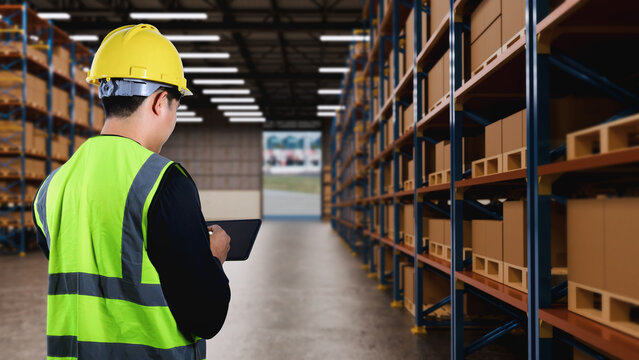 Warehouse Worker with Tablet Checking Inventory in Large Distribution Center Storage Facility