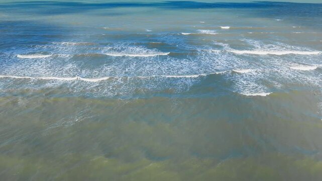 Blue green sea surface with wide wave bands and scattered whitewater, aerial drone view. Natural water pattern