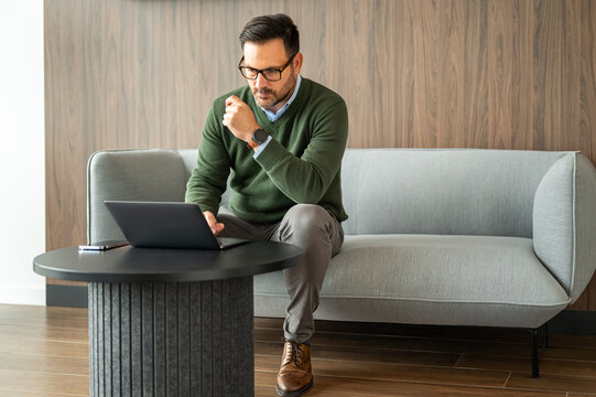 Businessman sitting on a couch. Diligently using a laptop for remote work and digital tasks