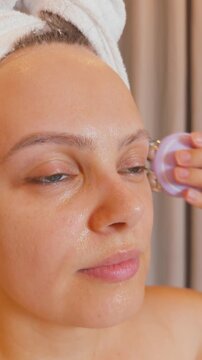 Woman applying microcurrent device to her face, performing a lifting and rejuvenating anti aging skincare treatment, promoting facial health, beauty, and wellness from home