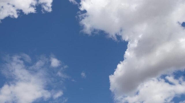 Timelapse of white cumulus clouds moving across blue sky