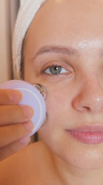Woman using a microcurrent facial device for at home skincare treatment, performing a rejuvenating massage to enhance beauty, reduce signs of aging, and achieve a radiant, toned appearance