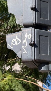 Close-up of street traffic light visor with white handwritten graffiti tag