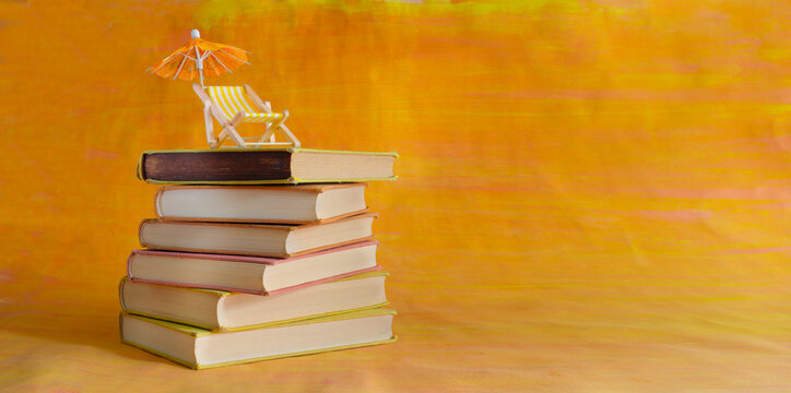 stack of books with deckchair and sun umbrella, spring and summer holiday read. Vacation,travel, inspiration,relaxation with books,reading and literature concept