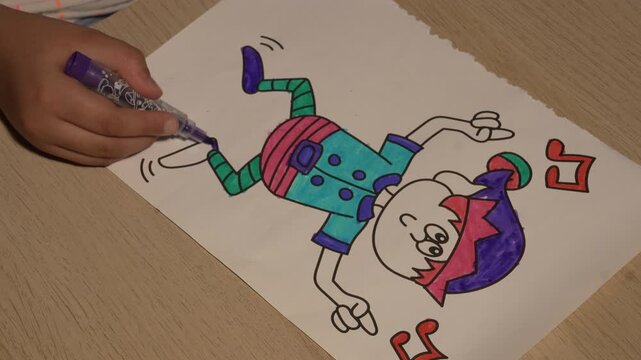 Child hands filling drawing with purple felt tip pen close up view
