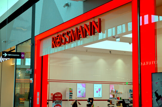 Modern bright red exterior signage and entrance of a Rossmann drugstore store inside a contemporary shopping mall interior.