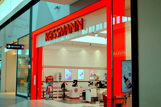 Modern bright storefront of a Rossmann pharmacy and cosmetics store located inside a contemporary shopping mall center.