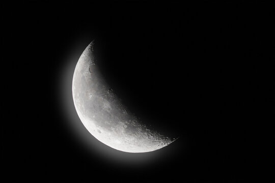 grey crescent moon shines with moonlight in the black sky