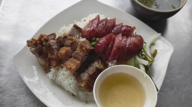 Vietnamese traditional lunch combo with crispy pork belly, Chinese sausage, white rice, fish sauce, and soup at a local eatery