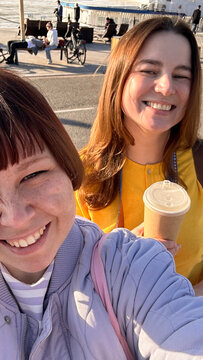Friends snap a selfie mid-laugh with coffees in hand