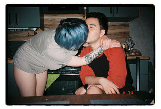 A couple share a spontaneous kiss in their kitchen
