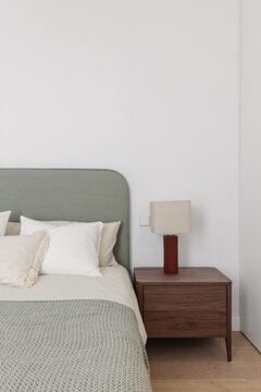 Sage green headboard with walnut nightstand and textured cushion