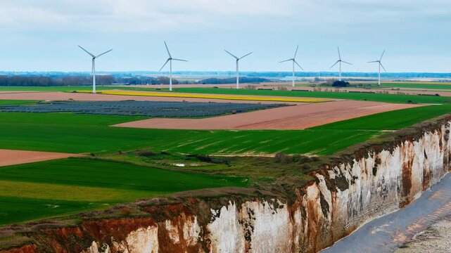 Wind farm and solar power field near chalk cliff coastline in Normandy, France. Renewable electricity production on English Channel coast