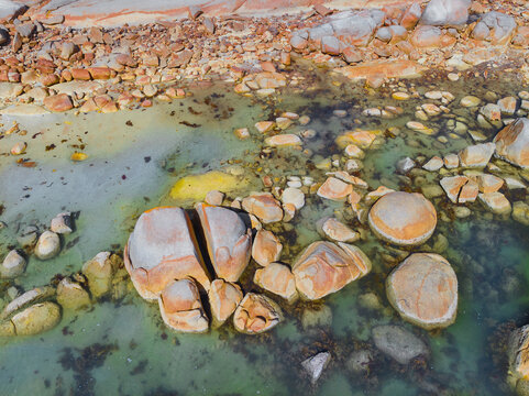 Weathered granite rocks with colored lichen along a rugged coastline