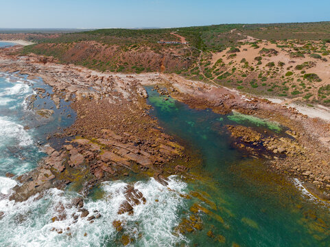 Waves breaking onto colorful rock reefs on a rugged remote coastline