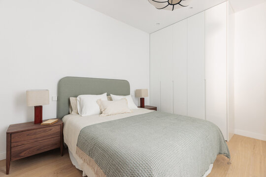 Bedroom with sage green headboard and walnut nightstands