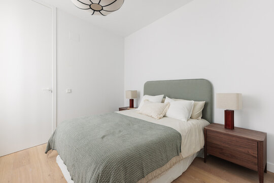 Bedroom viewed from doorway with sage green bed and sputnik pend